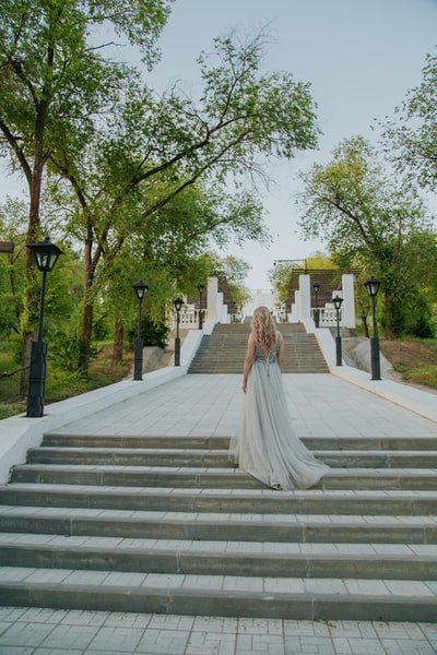 Wearing white clothes woman walking in the gray cement on the stairs
